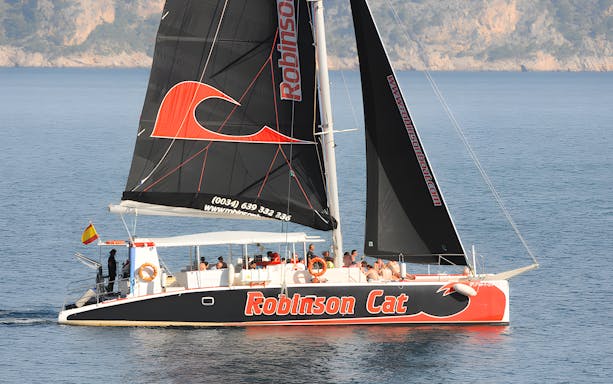 Catamaran sailing near Mallorca coast for sunrise and dolphin watching tour.