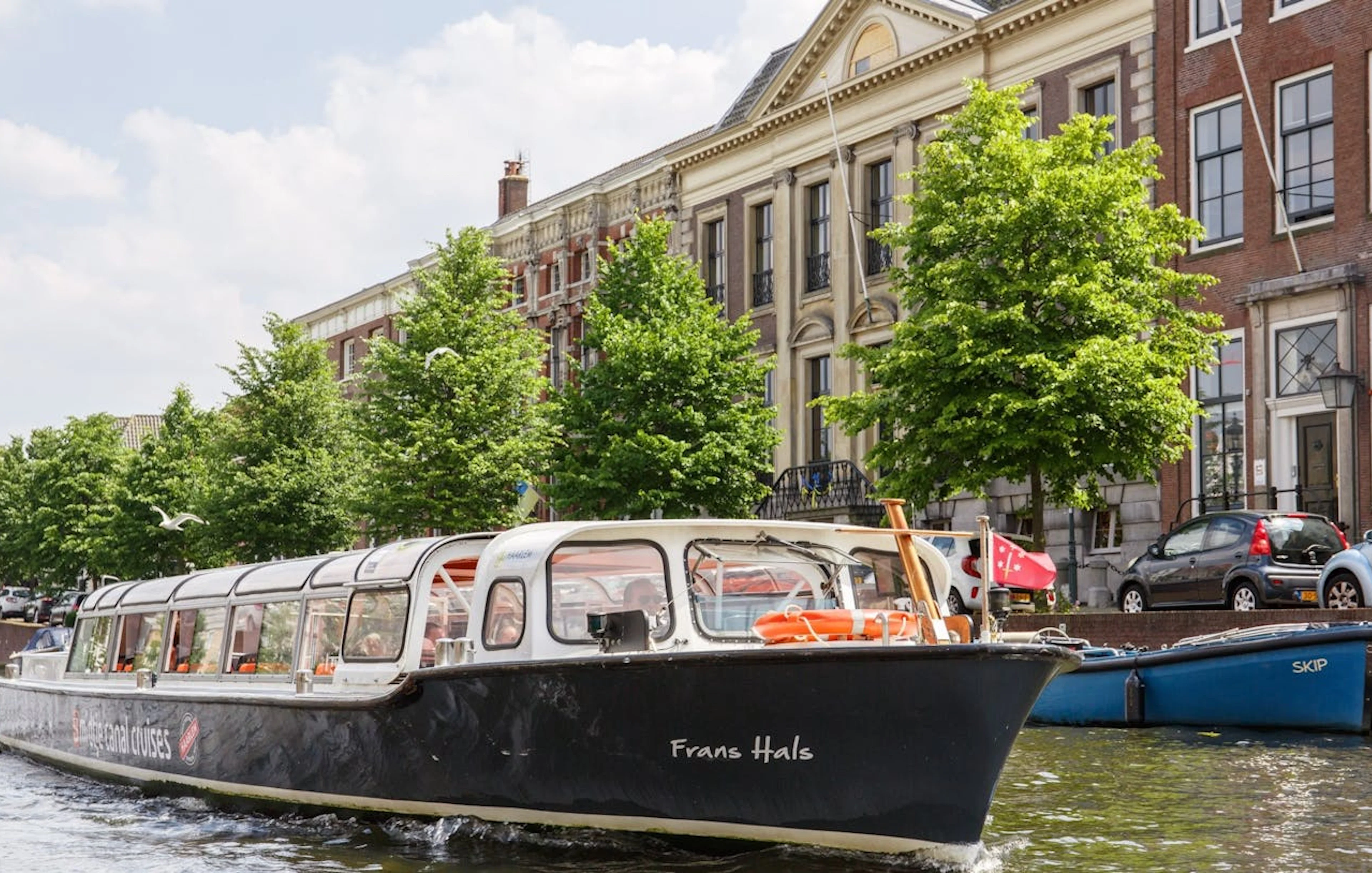 Haarlem canal cruise boat passing historical buildings.