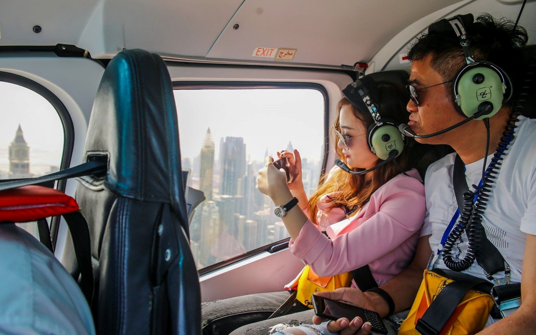 Visitors inside a helicopter over Dubai, capturing city skyline views.