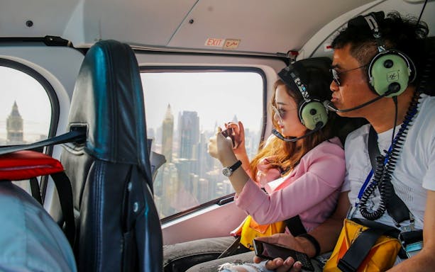 Visitors inside a helicopter over Dubai, capturing city skyline views.