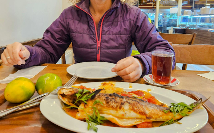 Guest dining on grilled fish with tea during Princes' Islands Sightseeing Cruise tour.