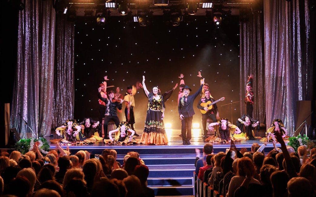 Flamenco dancers performing on stage in Granada with audience watching.