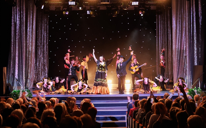 Flamenco dancers performing on stage in Granada with audience watching.
