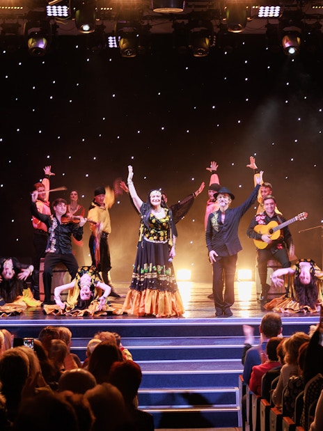 Flamenco dancers performing on stage in Granada with audience watching.