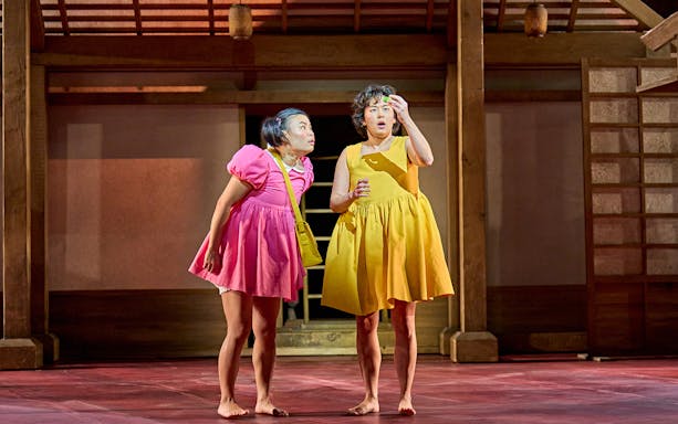 Two actors on stage in colorful dresses during a My Neighbour Totoro performance.