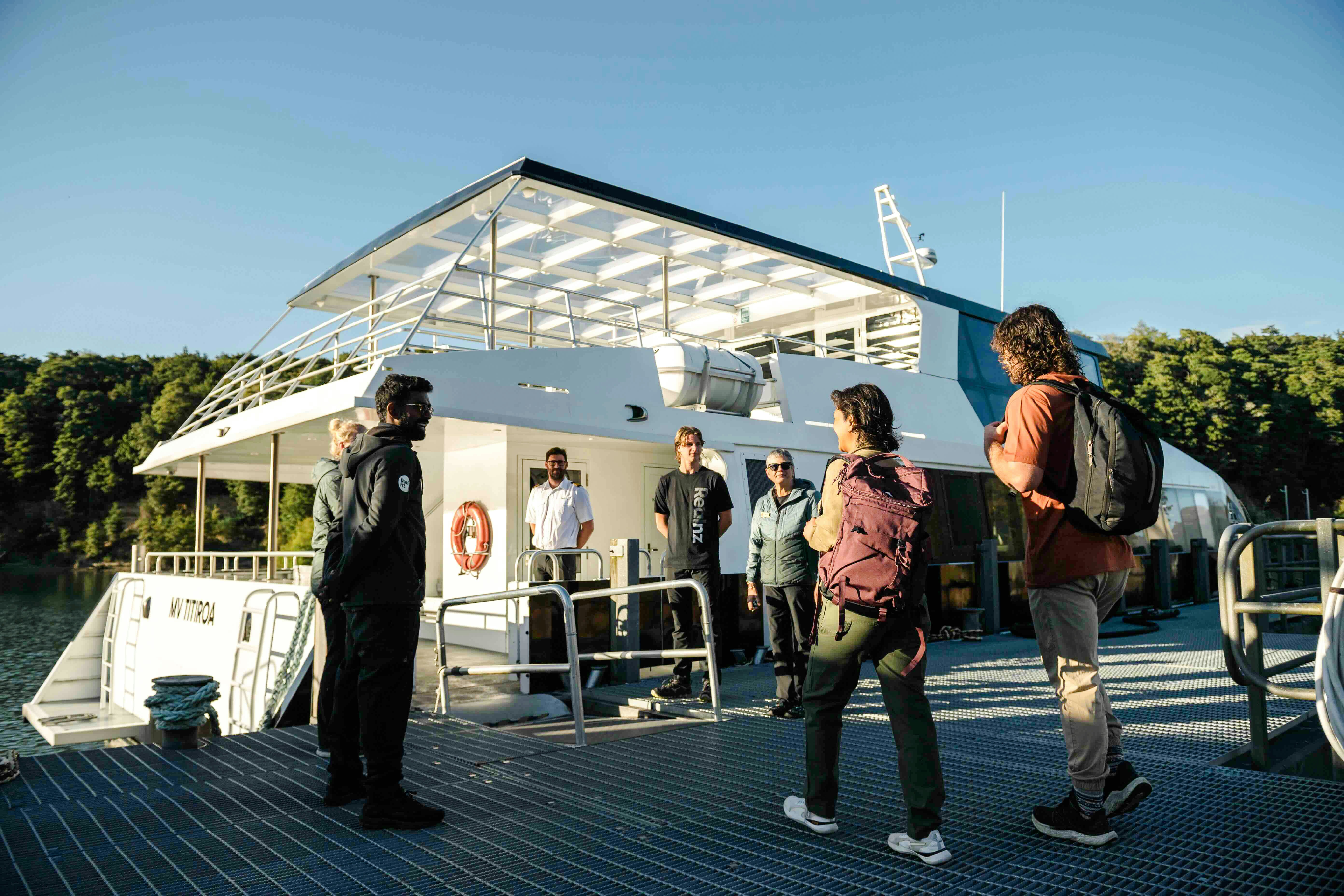 Passengers receive a briefing from the crew on the open deck of a boat in Doubtful Sound.
