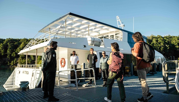 Passengers receive a briefing from the crew on the open deck of a boat in Doubtful Sound.