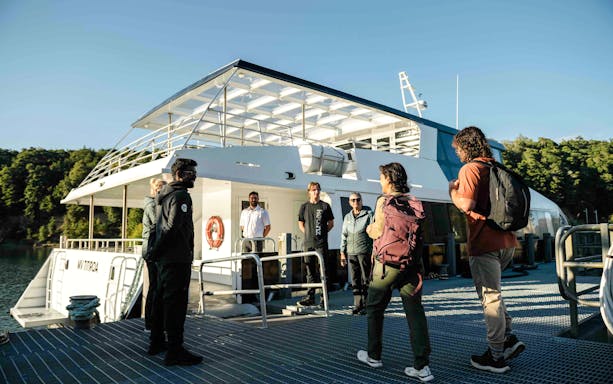 Passengers receive a briefing from the crew on the open deck of a boat in Doubtful Sound.
