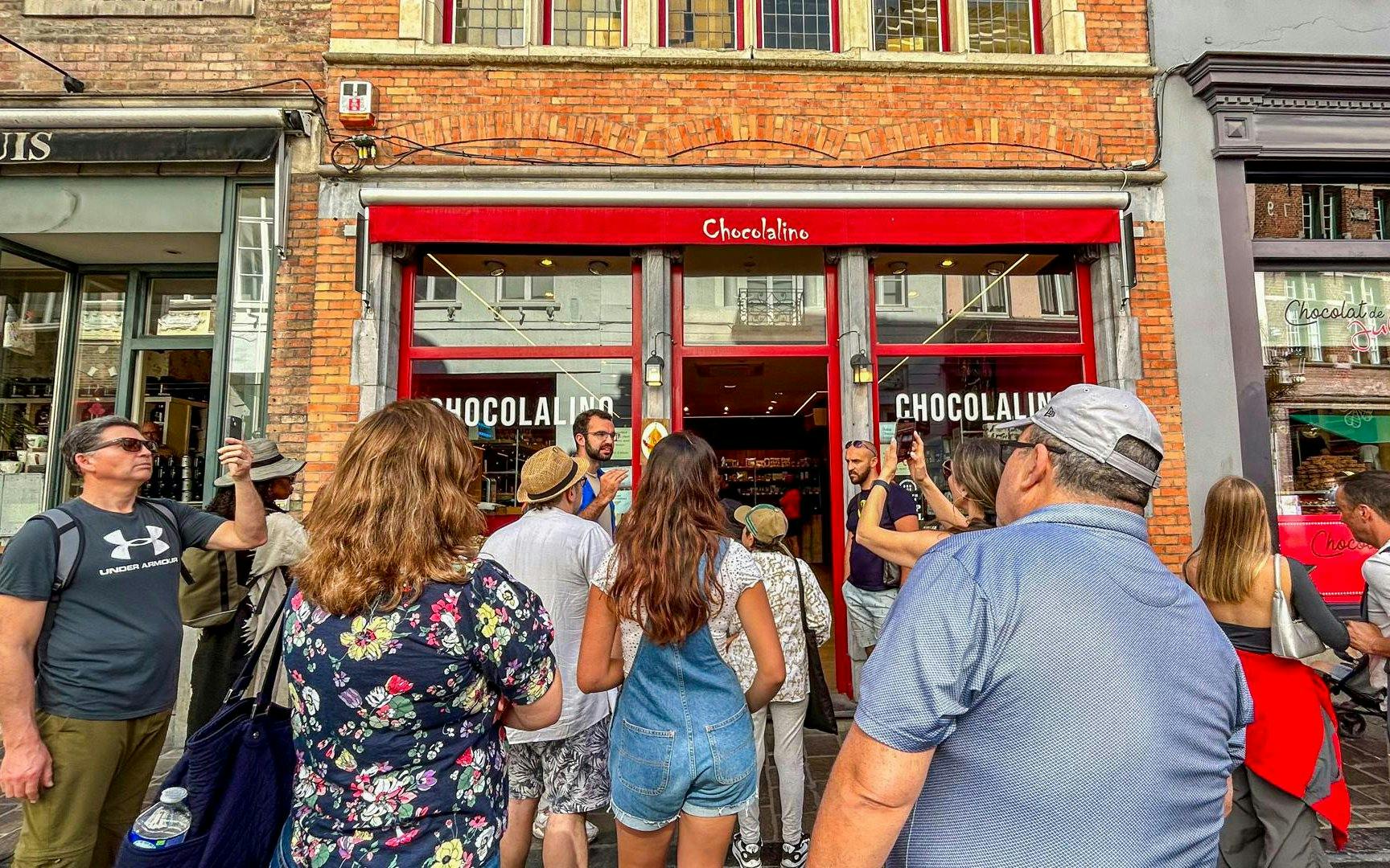 Guide leading a group outside Chocolalino in Brussels during the Brussels and Bruges tour.