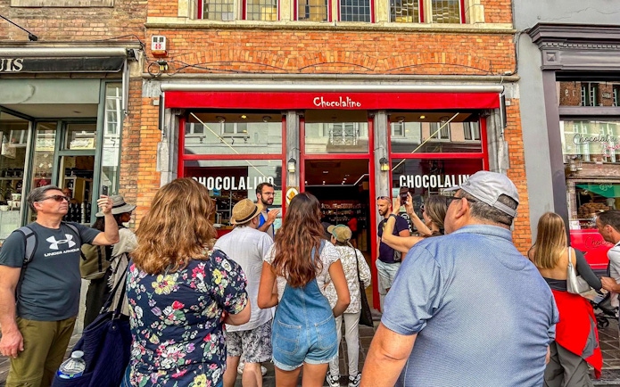 Guide leading a group outside Chocolalino in Brussels during the Brussels and Bruges tour.