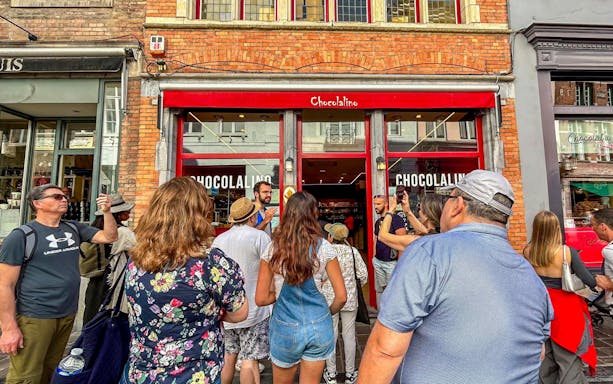 Guide leading a group outside Chocolalino in Brussels during the Brussels and Bruges tour.