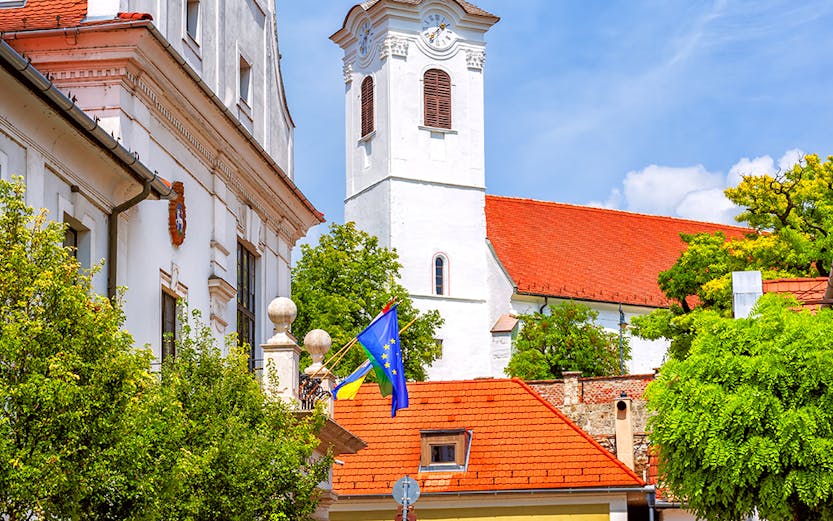 Historic street in Szentendre with colorful buildings and a church tower, Hungary.