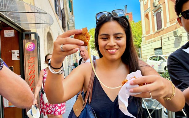 Tourist enjoying street food on Rome Trastevere food tour with local guide.