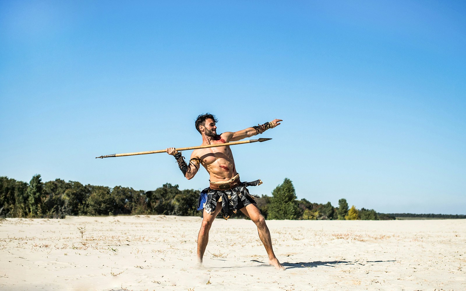 Man throwing spear on sandy beach in Hawaii.