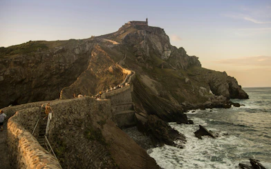 Stone path leading to San Juan de Gaztelugatxe chapel on rocky hill, Spain.