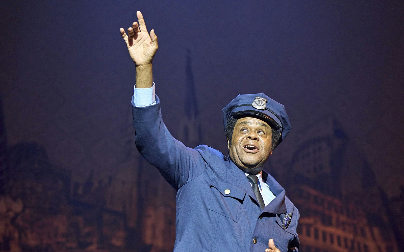 Performer in police uniform on stage during Sister Act musical.