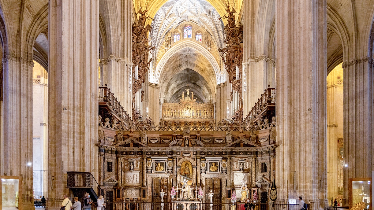 Seville Cathedral interior with ornate altar and vaulted ceilings.