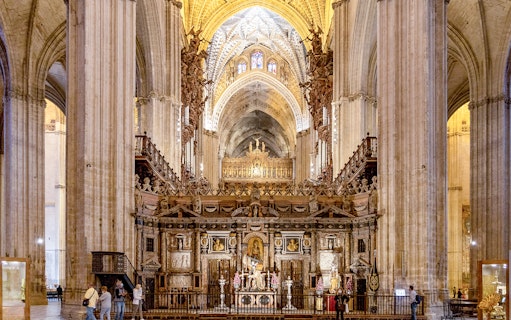 Seville Cathedral interior with ornate altar and vaulted ceilings.
