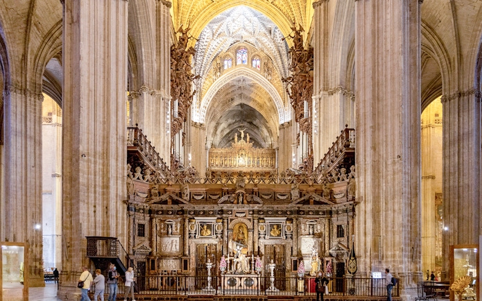 Seville Cathedral interior with ornate altar and vaulted ceilings.