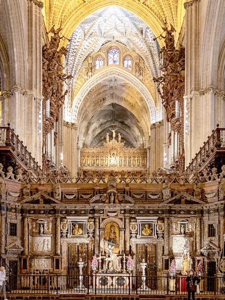 Seville Cathedral interior with ornate altar and vaulted ceilings.