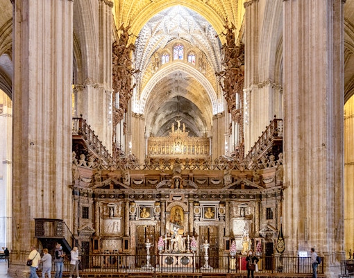 Seville Cathedral interior with ornate altar and vaulted ceilings.