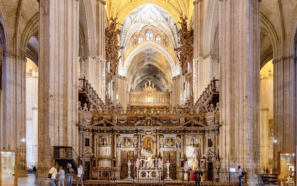 Seville Cathedral interior with ornate altar and vaulted ceilings.
