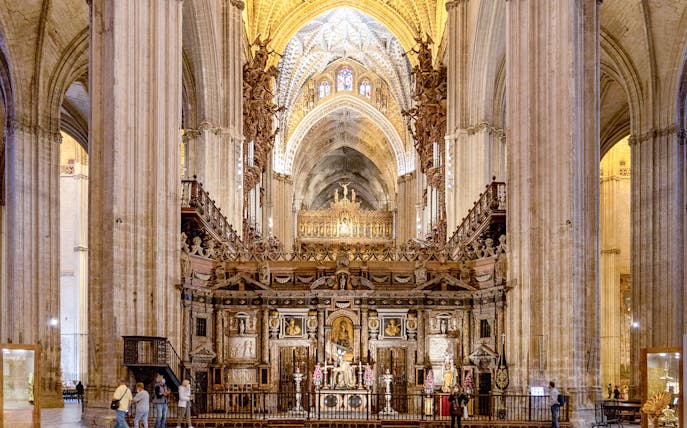 Seville Cathedral interior with ornate altar and vaulted ceilings.