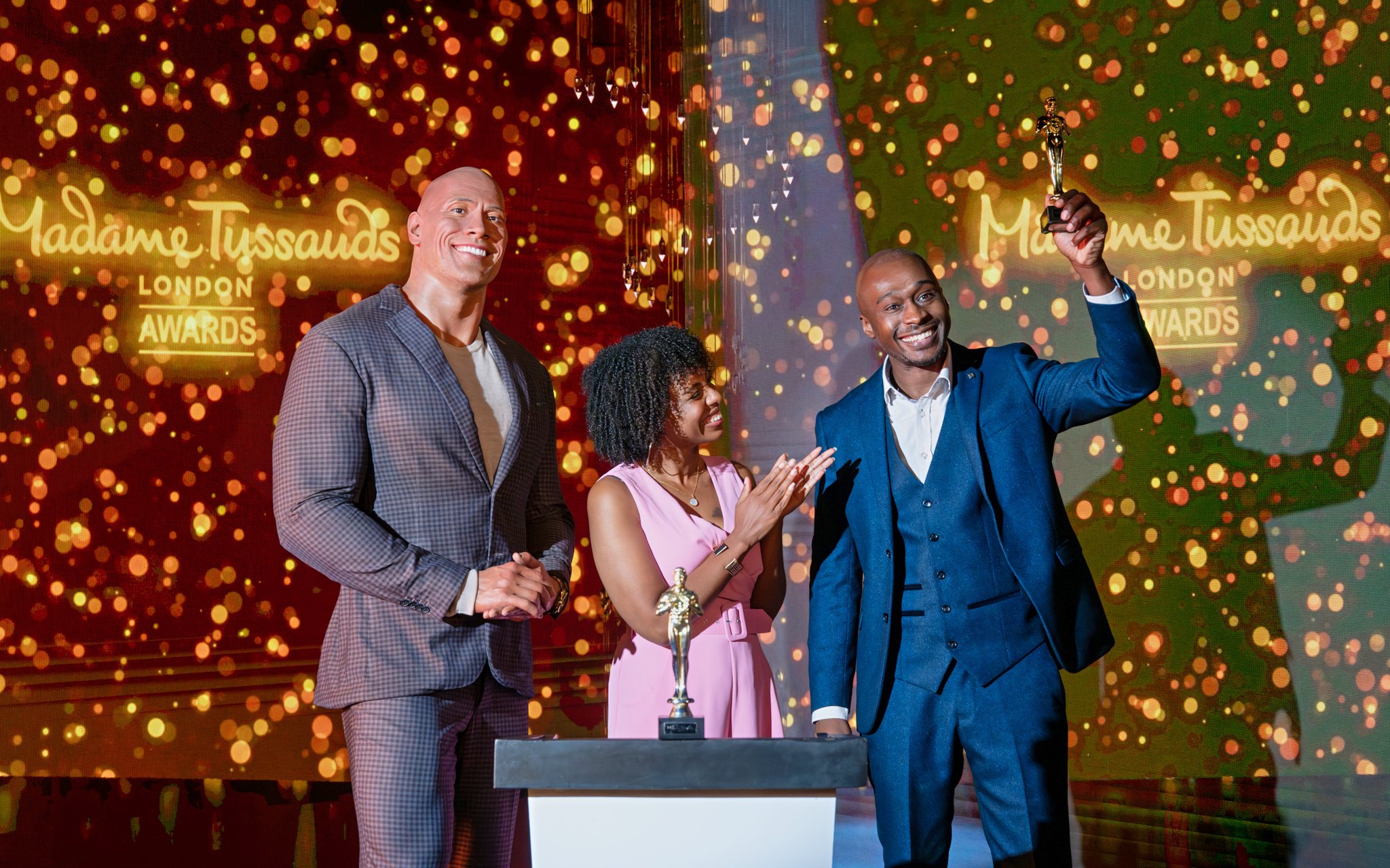 Award ceremony at Madame Tussauds London with wax figure and guests celebrating.