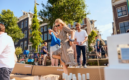 People enjoying a canal cruise in Amsterdam with drinks on board.