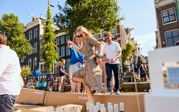 People enjoying a canal cruise in Amsterdam with drinks on board.