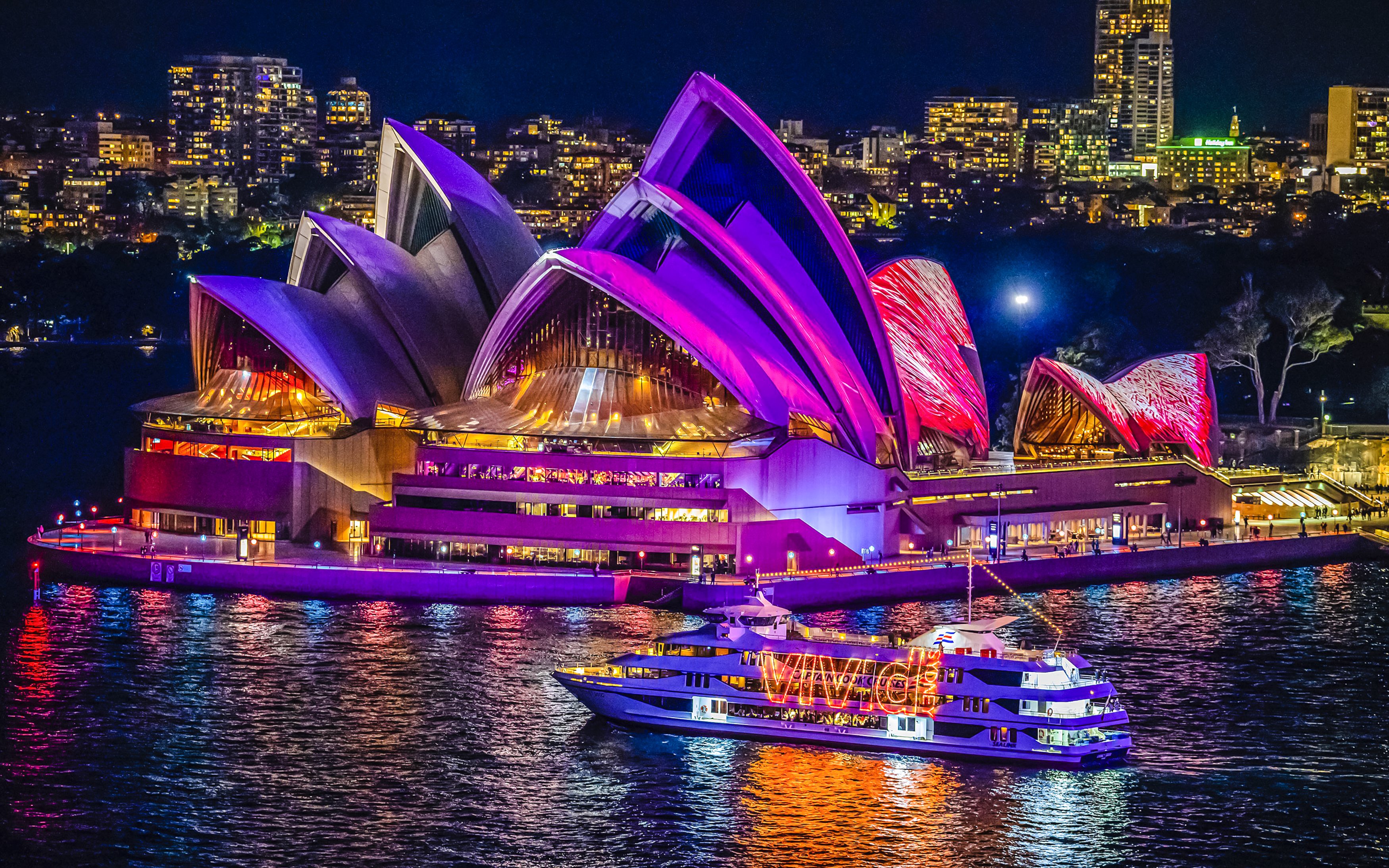 Sydney Opera House illuminated during harbour light show cruise.