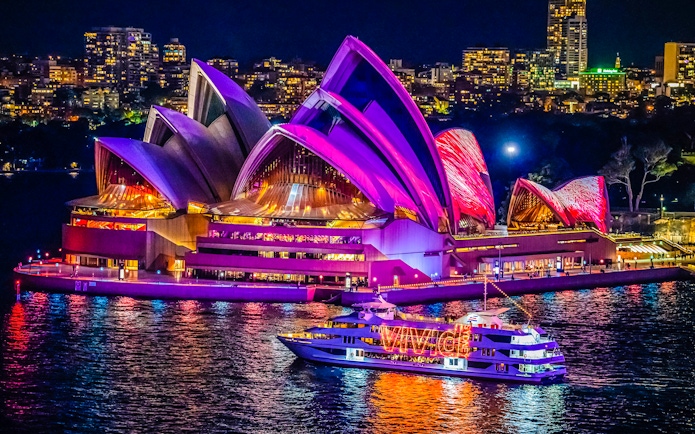 Sydney Opera House illuminated during harbour light show cruise.