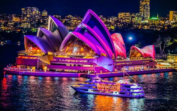 Sydney Opera House illuminated during harbour light show cruise.