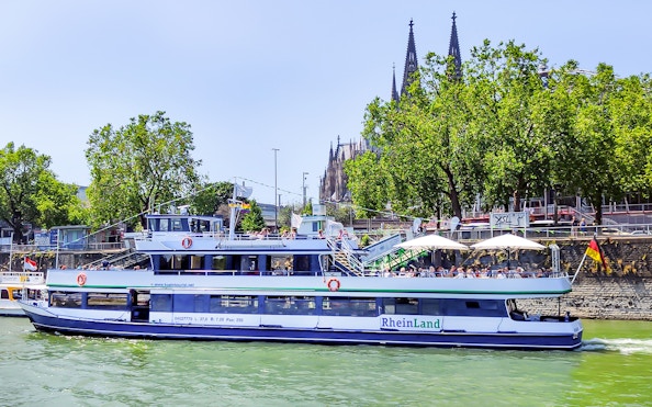 Harbor cruise boat on the Rhine River with Cologne Cathedral in the background.