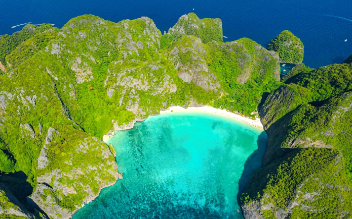 Aerial view of turquoise bay surrounded by lush cliffs on Phi Phi Islands, Phuket.