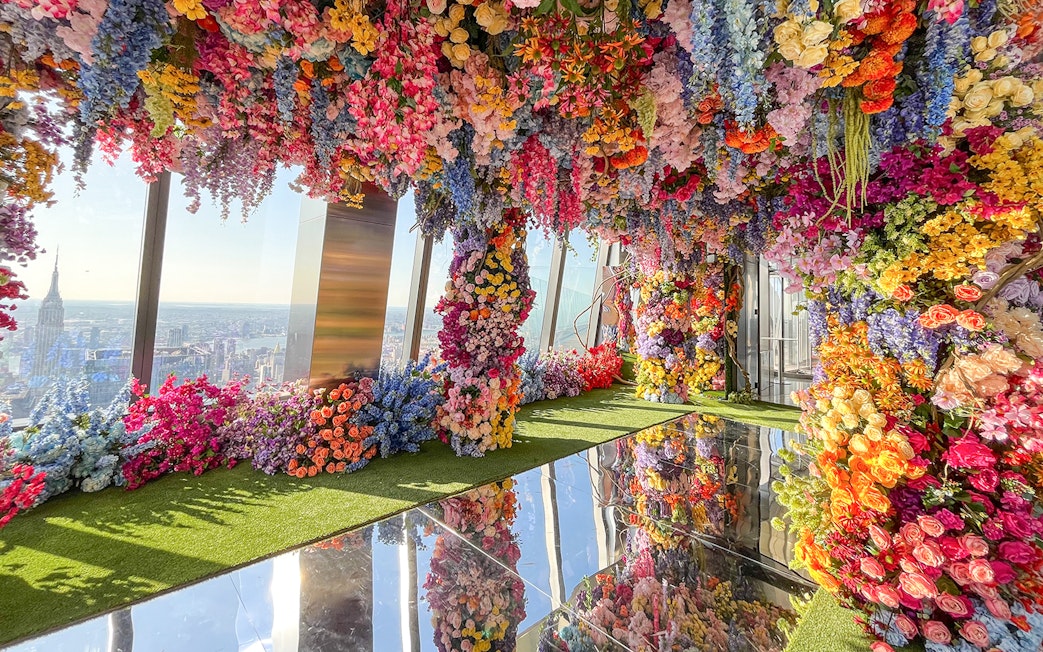 Colorful floral installation at Top of the Rock Observation Deck with city skyline view.