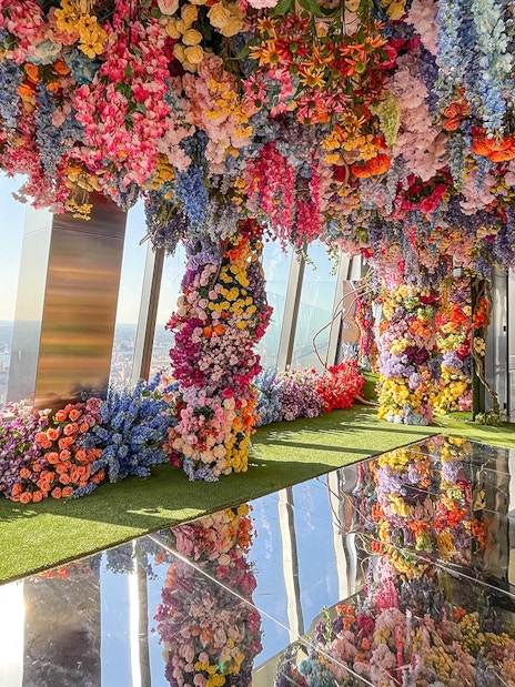 Colorful floral installation at Top of the Rock Observation Deck with city skyline view.
