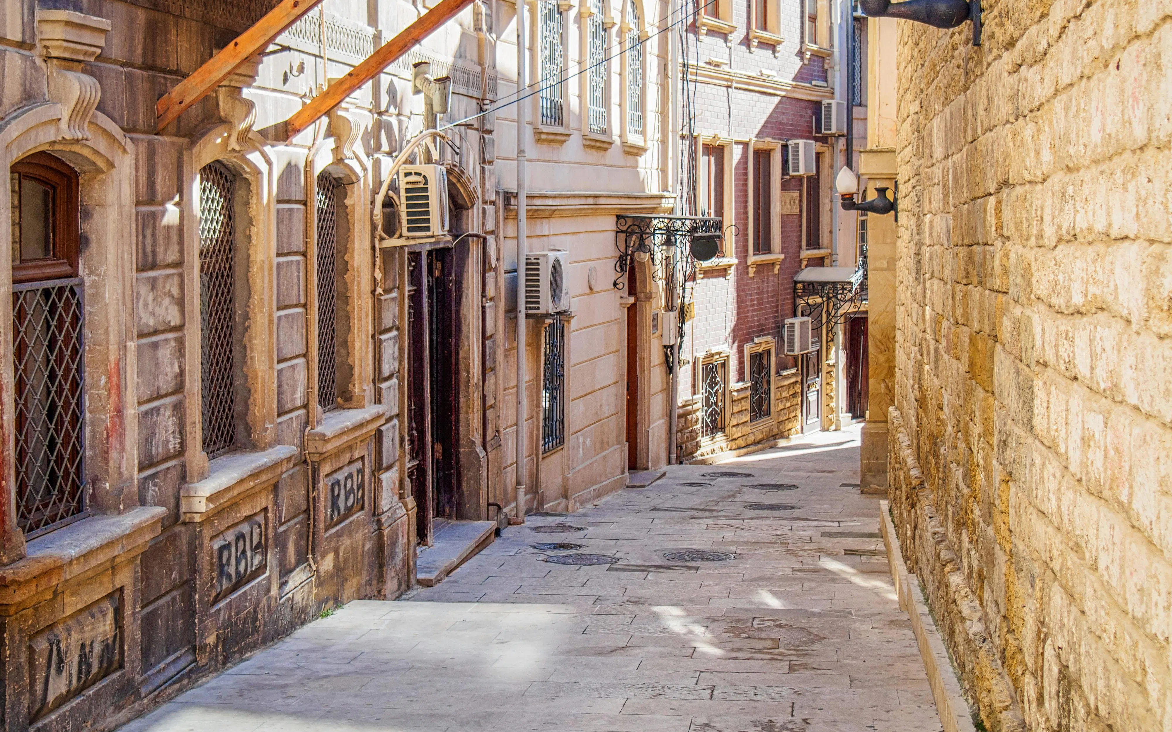 Narrow cobblestone street in Baku old town with historic stone buildings.