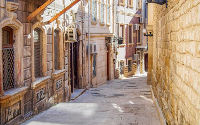 Narrow cobblestone street in Baku old town with historic stone buildings.