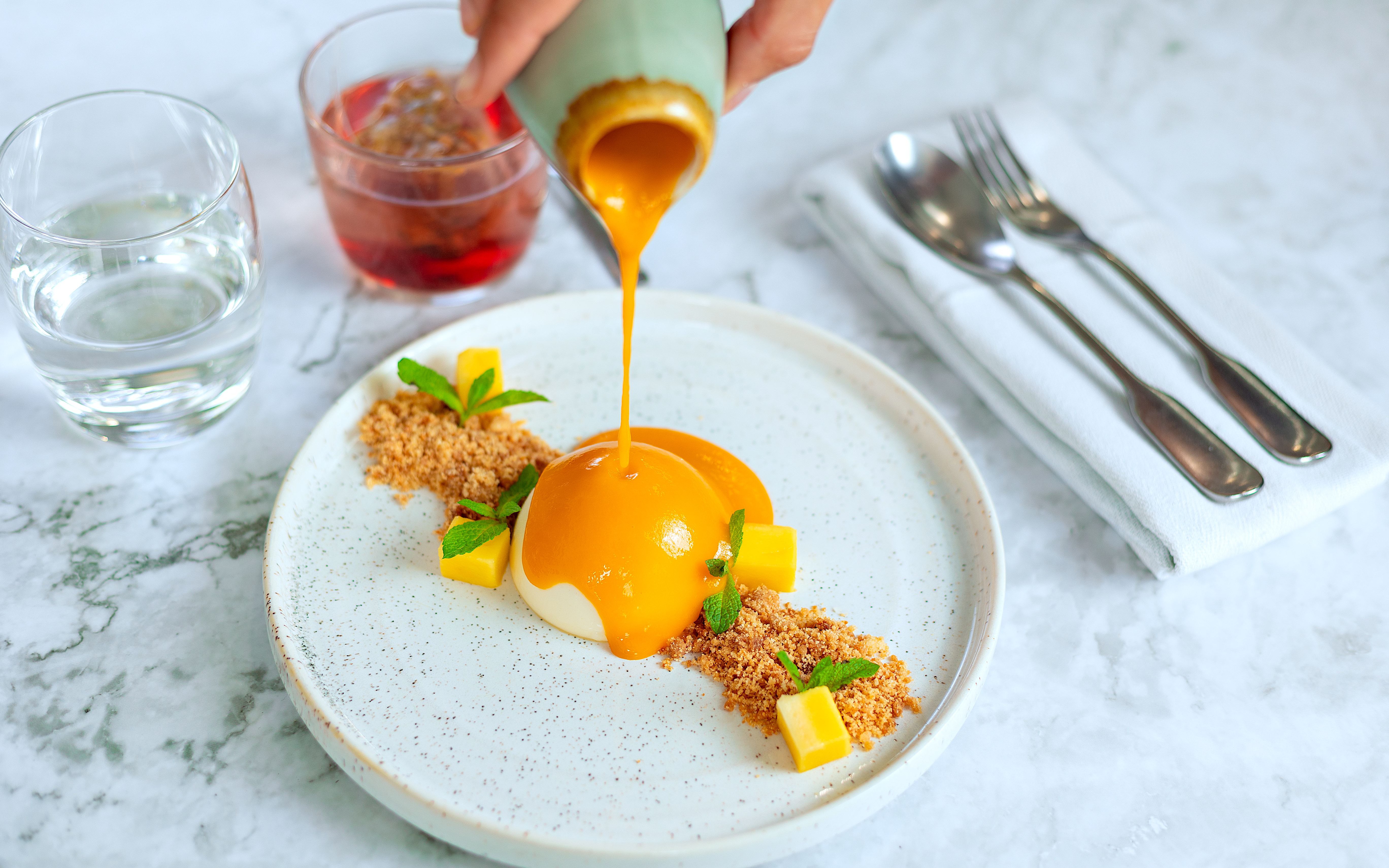 Dessert being served on Bustronome London tour with mango sauce and garnish.