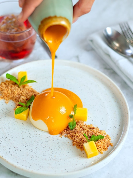 Dessert being served on Bustronome London tour with mango sauce and garnish.