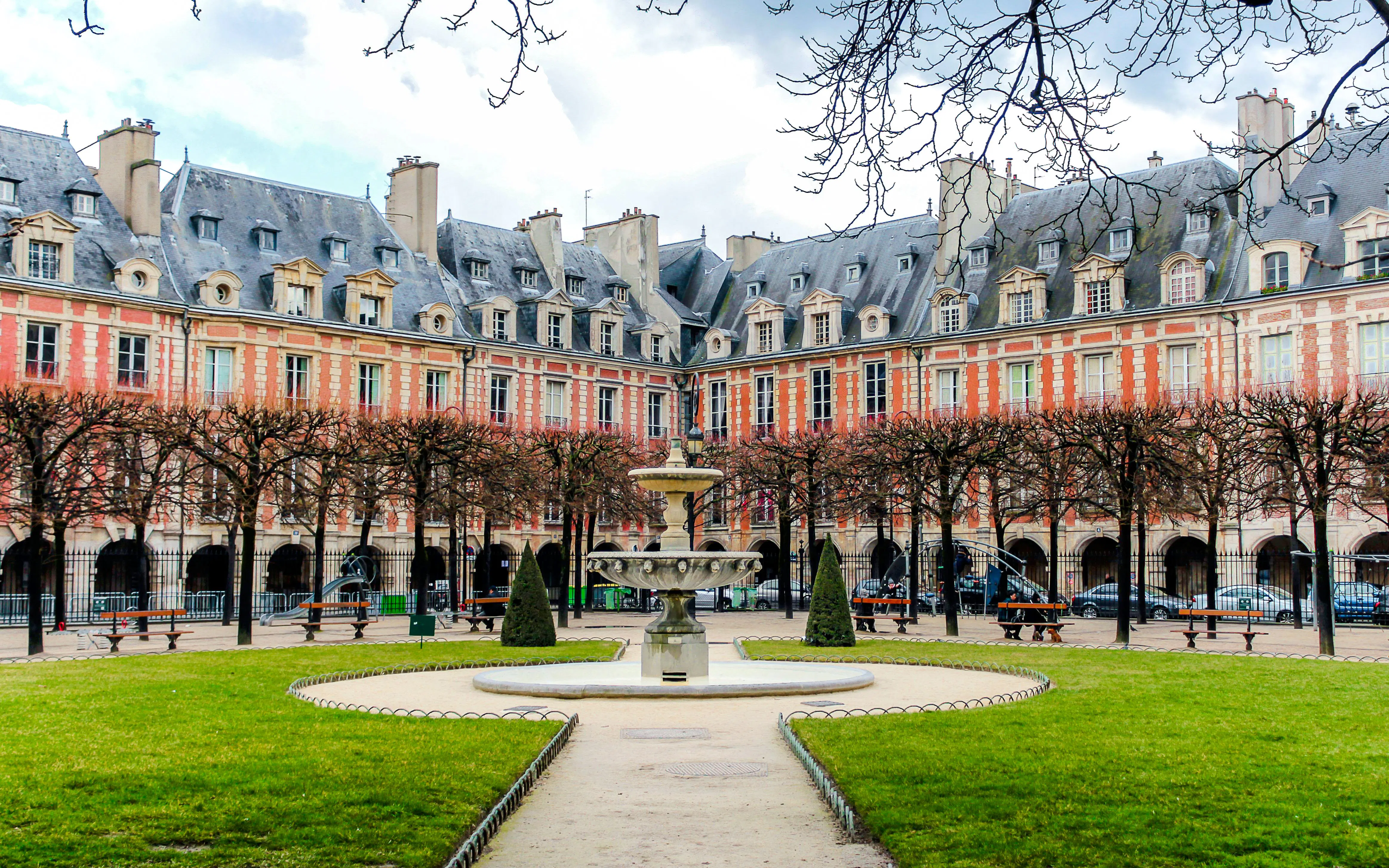 Place des Vosges courtyard with fountain and historic buildings, Paris walking tour.