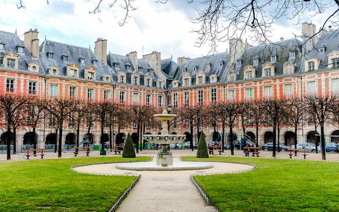 Place des Vosges courtyard with fountain and historic buildings, Paris walking tour.