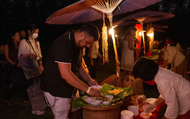 People serving traditional food under lanterns at Yeepeng Lanna Festival 2023.
