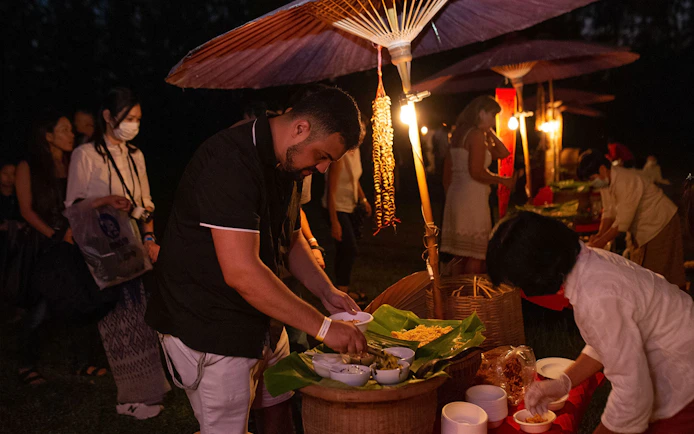 People serving traditional food under lanterns at Yeepeng Lanna Festival 2023.