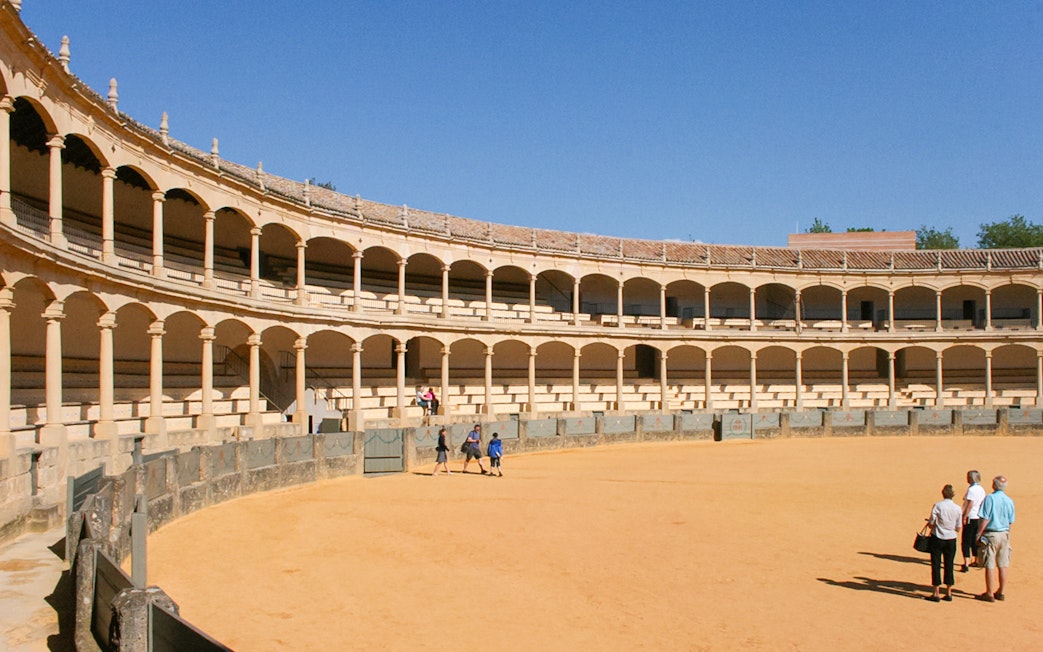 Ronda bullring with tourists on a guided tour in Setenil de las Bodegas, Spain.
