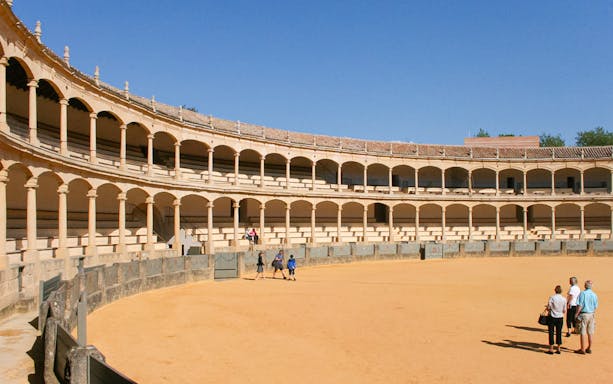 Ronda bullring with tourists on a guided tour in Setenil de las Bodegas, Spain.
