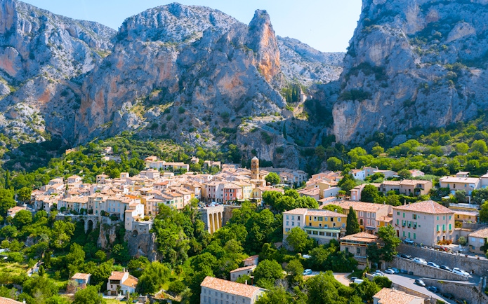 Village nestled in the Gorges du Verdon with rocky cliffs and greenery, France.