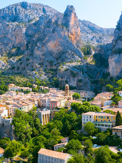 Village nestled in the Gorges du Verdon with rocky cliffs and greenery, France.