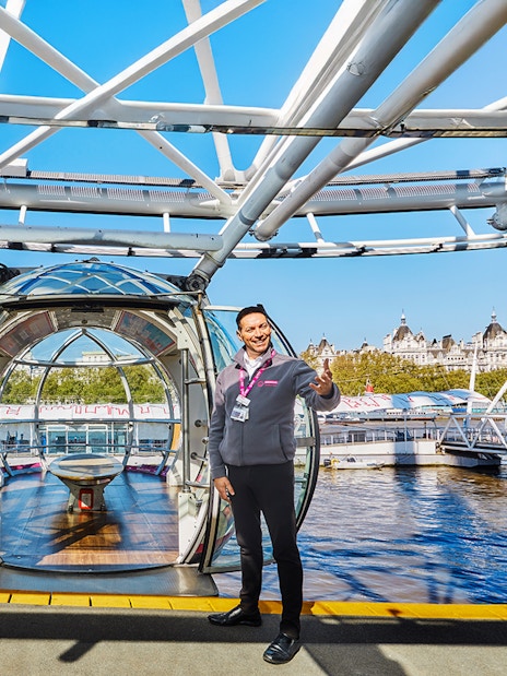 London Eye capsule entrance with staff welcoming visitors, view of Thames River.
